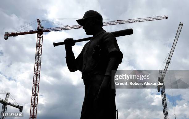 Silhouetted bronze statue of a baseball player in front of Coors Fields in Denver, Colorado, the home stadium for the Colorado Rockies Major League...