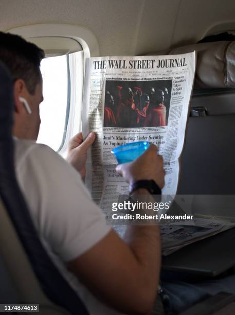 Passenger reads The Wall Street Journal during a flight originating from Denver International Airport in Denver, Colorado.