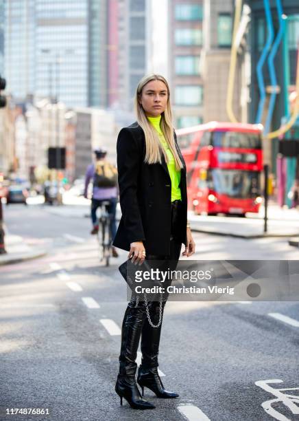 Nina Suess is seen wearing total look Marc Cain: black bag, black vinyl pants, ankle boots, blazer, neon turtleneck during London Fashion Week...