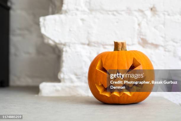 halloween pumpkin lantern in front of a white brick wall - lanterna de halloween - fotografias e filmes do acervo