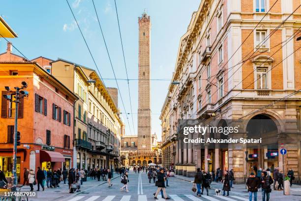 street in bologna with asinelli tower in the center, emilia romagna, italy - bolonha imagens e fotografias de stock