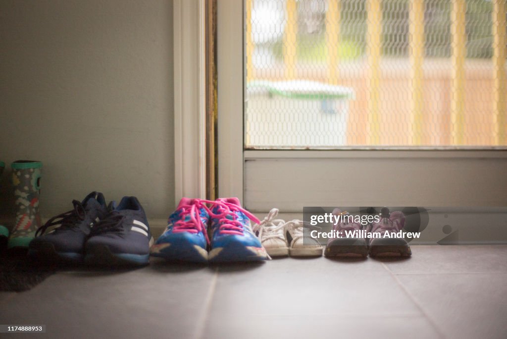 Family of shoes of different sizes sitting near home door