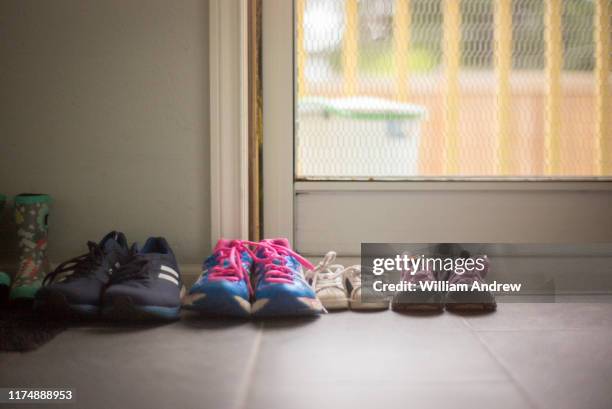 family of shoes of different sizes sitting near home door - family shoes stockfoto's en -beelden