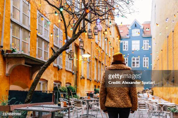 rear view of a young woman in a fake fur coat in the streets of copenhagen, denmark - winter denmark stock pictures, royalty-free photos & images