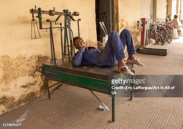 Eritrean man resting on a weighing scale in the grain market, Central region, Asmara, Eritrea on August 21, 2019 in Asmara, Eritrea.
