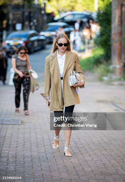 Guest is seen wearing beige blazer, cropped pants, white bag outside Rocha during London Fashion Week September 2019 on September 15, 2019 in London,...