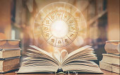 Love horoscope, zodiac sign astrology for foretell and fortune telling education study course concept with horoscopic wheel over old love story book in school library
