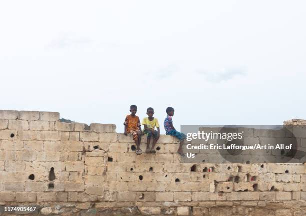 Eritrean boys sit on a wall with bullet holes, Debub, Ghinda, Eritrea on August 14, 2019 in Ghinda, Eritrea.