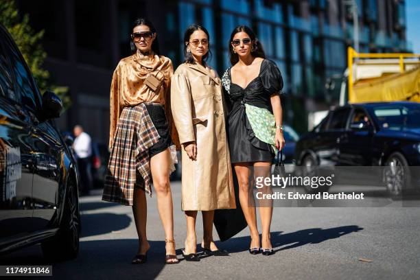 Doina Ciobanu wears sunglasses, a golden shiny silky flowy top with printed features, a brown mini bag attached to the top, a tartan checked pattern...