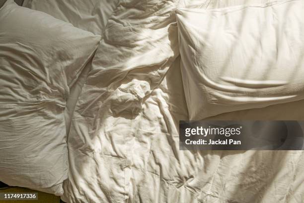 messy white sheet on bed - beds photos et images de collection