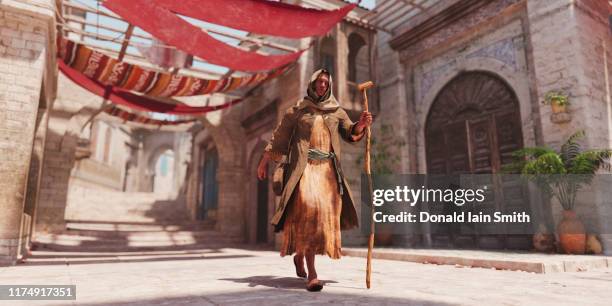 man with staff walking though souk - ground staff photos et images de collection