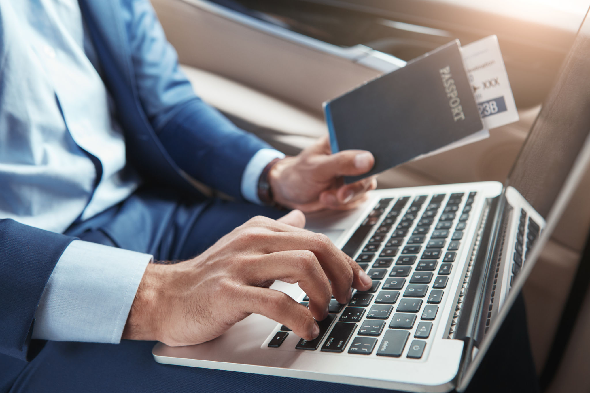 Check in. Cropped image of young businessman in formal wear working on laptop and holding passport with flight tickets while sitting in car. Check in. Cropped image of young businessman in formal wear working on laptop and holding passport with flight tickets while sitting in car.