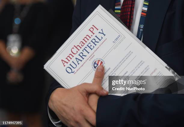 Participant holds a copy of 'AmCham.Pl' - the official magazine of the American Chamber of Commerce in Poland, during Congress 590 economic forum, in...