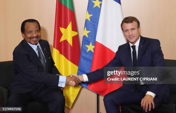 French President Emmanuel Macron shakes hands with Cameroon President Paul Biya prior bilateral talks in Lyon, central eastern France, on October 10...