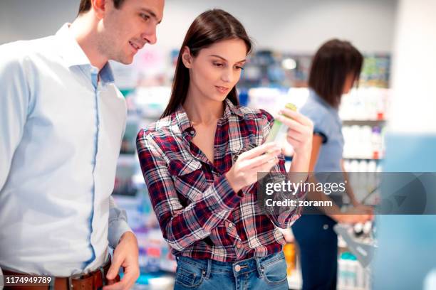 woman choosing of shampoo and looking at the label with partner - cosmetic testing store stock pictures, royalty-free photos & images