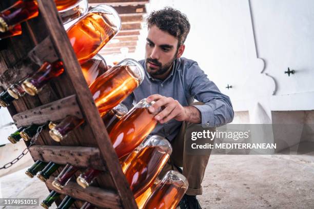 winemaker draaien rose wijnflessen - wijnbouw stockfoto's en -beelden