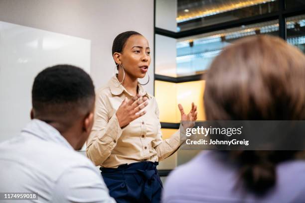 jonge zakenvrouw uitleggen en gebaren in vergadering - positive business stockfoto's en -beelden