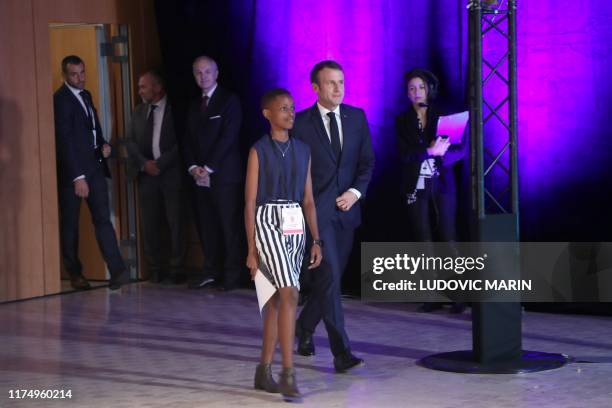 French president Emmanuel Macron and Burundi's Amanda Dushime who comes to testify about her HIV sickness arrive on stage in Lyon, central eastern...