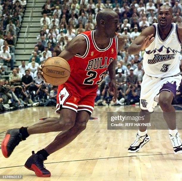 Michael Jordan of the Chicago Bulls goes to the basket past Bryon Russell of the Utah Jazz 11 June during game five of the 1997 NBA Finals at the...