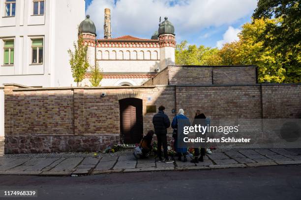 People mourn in front of the entrance to the Jewish synagogue on October 10, 2019 in Halle, Germany. Law enforcement authorities, after initially...