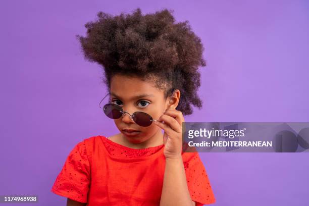 ethnic kid girl looking camera lowering sunglasses - red eyeglasses stock pictures, royalty-free photos & images