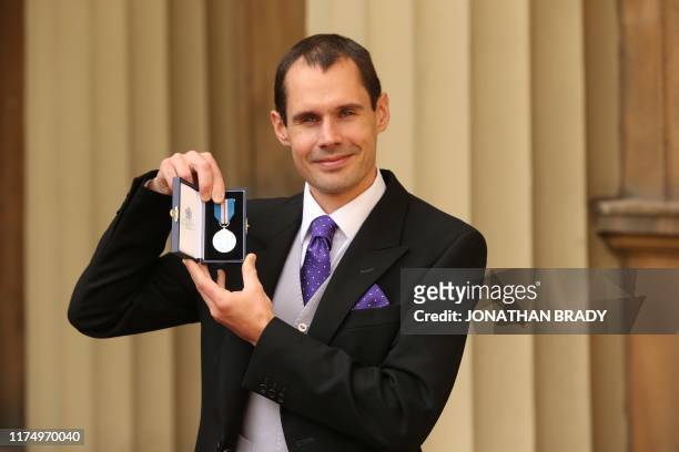 Christopher Jewell poses with The Queen's Gallantry Medal after an investiture ceremony at Buckingham Palace in London on October 10 for services to...