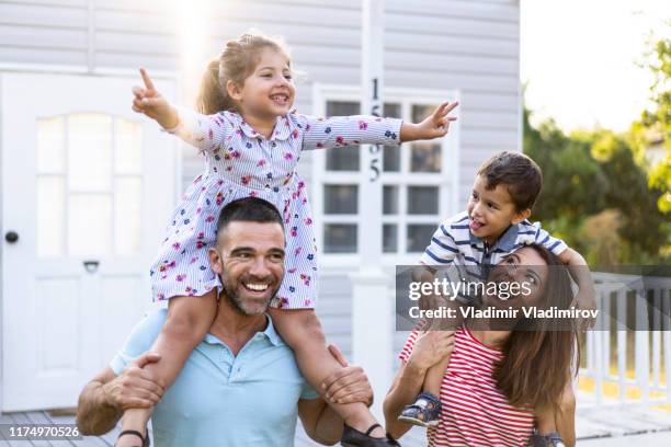 famiglia che si diverte nel giro in piggyback di fronte alla casa - family porch foto e immagini stock