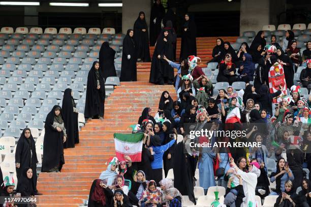 Iranian women cheer and wave their country's national flags as they attend the World Cup Qatar 2022 Group C qualification football match between Iran...