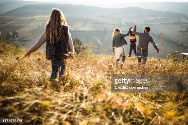 back view of playful parents swinging their son on a hill. - exclusion stock pictures, royalty-free photos & images