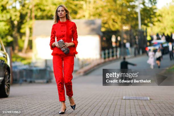 Lauren Santo Domingo wears a red jacket with floral embroidery and a fluffy collar, red pants, black leather shoes, earrings, during London Fashion...
