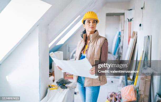 female architect looking at blueprints on construction site - attic conversion stock pictures, royalty-free photos & images