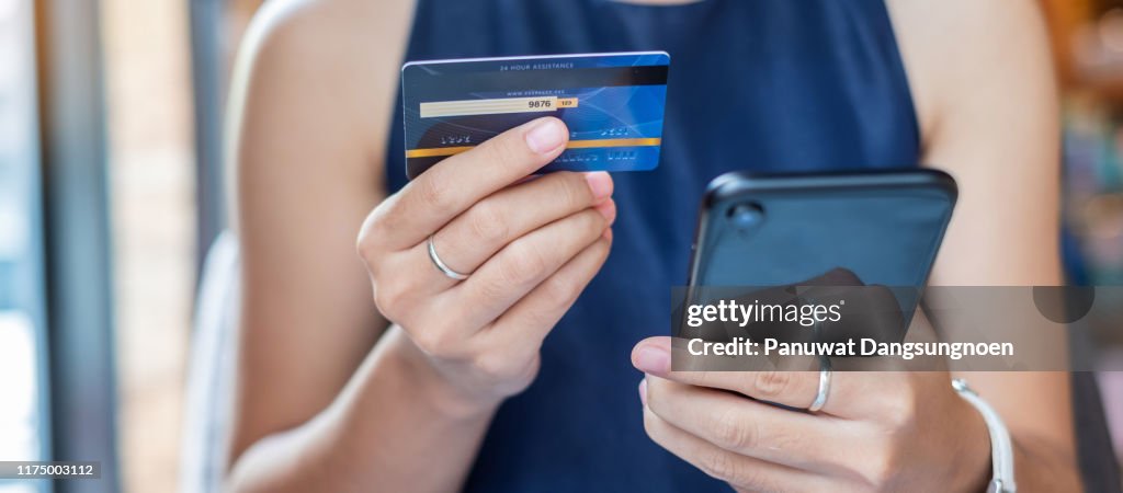 Midsection Of Woman Holding Credit Card While Using Mobile Phone For Online Shopping
