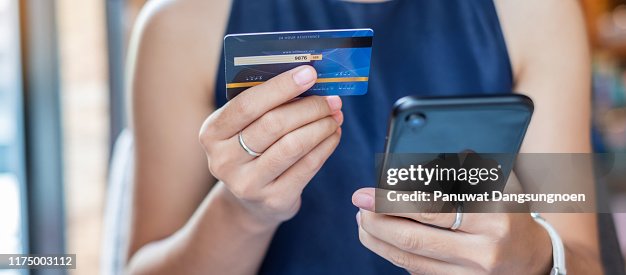 Midsection Of Woman Holding Credit Card While Using Mobile Phone For Online Shopping Midsection Of Woman Holding Credit Card While Using Mobile Phone For Online Shopping
