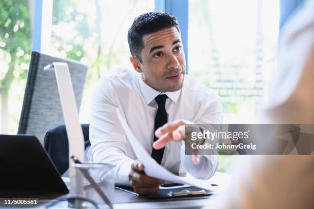 mid 30s businessman explaining merits of plan to colleague - persuasão imagens e fotografias de stock