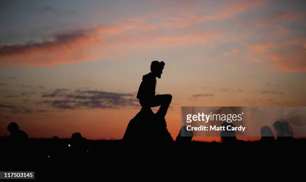 Festival-goers gather to see the sunrise from the Stone Circle area at the Glastonbury Festival site at Worthy Farm, Pilton on June 27, 2011. This...