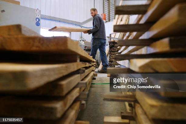The Woodworkers Shoppe employees Jamie Yoder loads pieces of mountain pine beetle-killed ponderosa pine into a molding machine September 12, 2019 in...