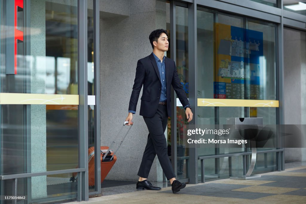Businessman with suitcase leaving airport