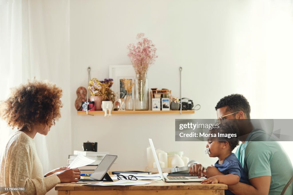 Pais que usam o computador ao sentar-se com menino