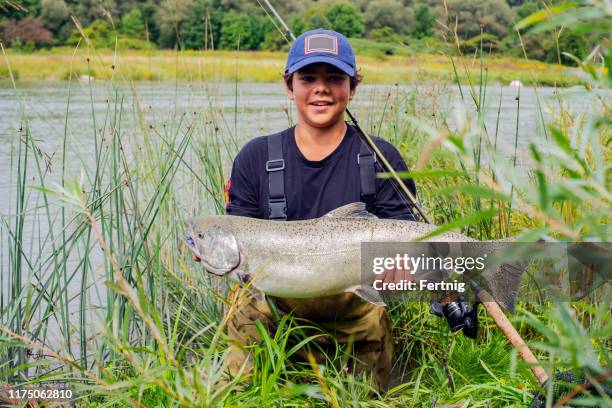un giovane pescatore orgoglioso con un salmone chinook (salmone re) che ha catturato. - catching fish foto e immagini stock