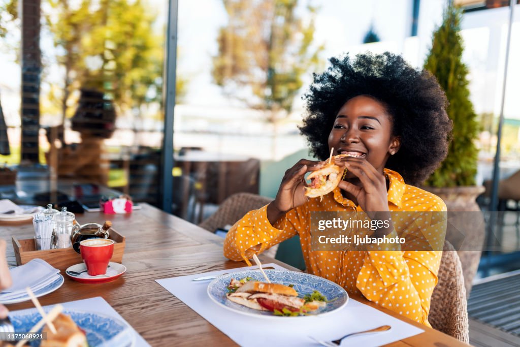 Vrouw genieten van sandwich eten in restaurant