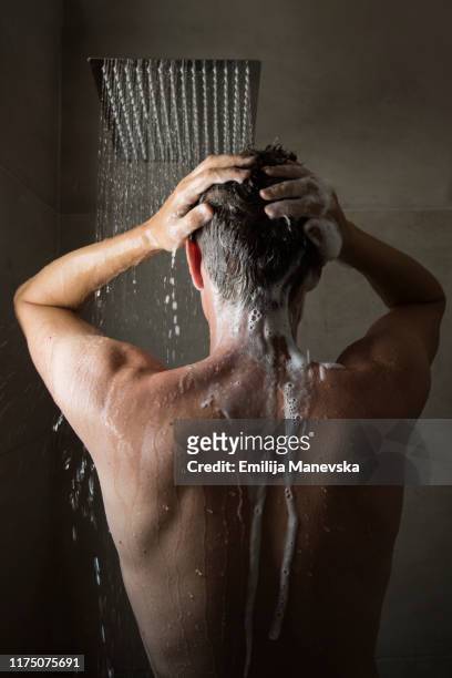 young man under the shower in bathroom - strong hair 個照片及圖片檔