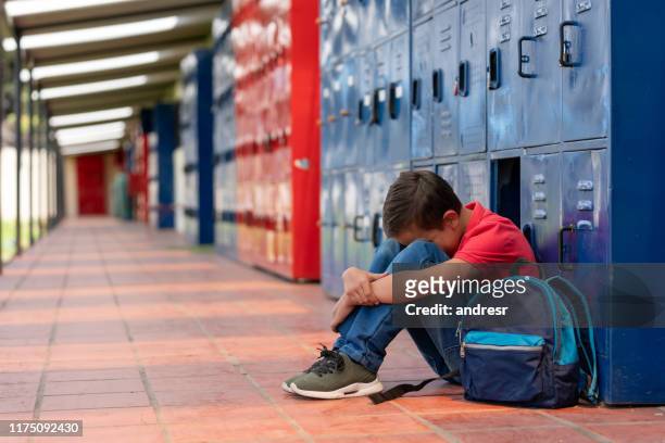 triste chico en la escuela llorando por ser intimidado - violencia escolar fotografías e imágenes de stock