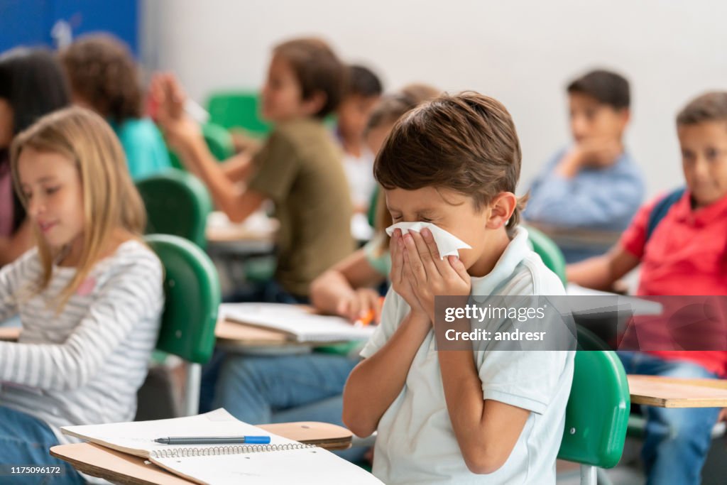 Sick boy at the school blowing his nose in class