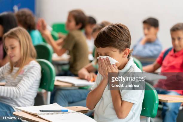 sick boy at the school blowing his nose in class - blowing nose stock pictures, royalty-free photos & images