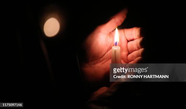 Mourner holds a candle at the synagogue in Halle and der Saale, eastern Germany, on October 10, 2019 one day after the deadly anti-Semitic shooting....