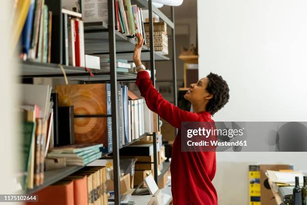 businesswoman taking book from shelf in office - shelf strip stock pictures, royalty-free photos & images