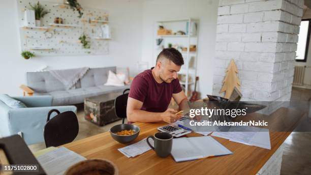 young man at home, paying bills online - home finances stock pictures, royalty-free photos & images