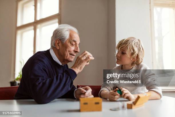 watchmaker and his grandson examining watch together - sponsor stockfoto's en -beelden