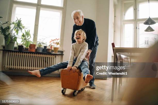 happy grandfather and grandson playing with buck at home - active senior man stockfoto's en -beelden