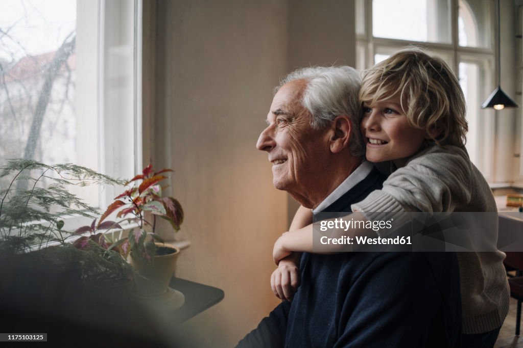 Happy grandson embracing grandfather at home